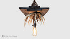 A rustic hanging light fixture featuring a dark wood square plate, a cluster of natural antlers, and a single exposed Edison bulb suspended below on a light gray background.