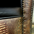 Close-up of a chair with crocodile embossed leather and nailheads.