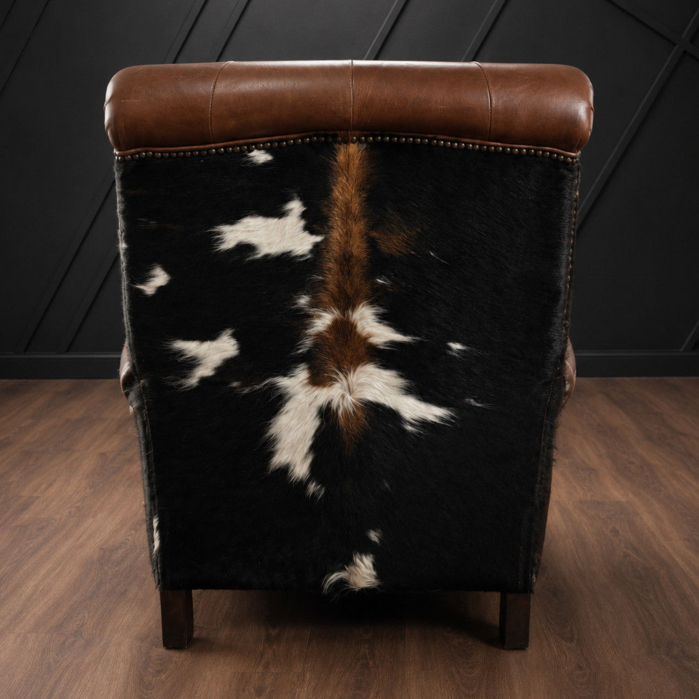 Recliner with cowhide and brown leather backrest against a dark wall.
