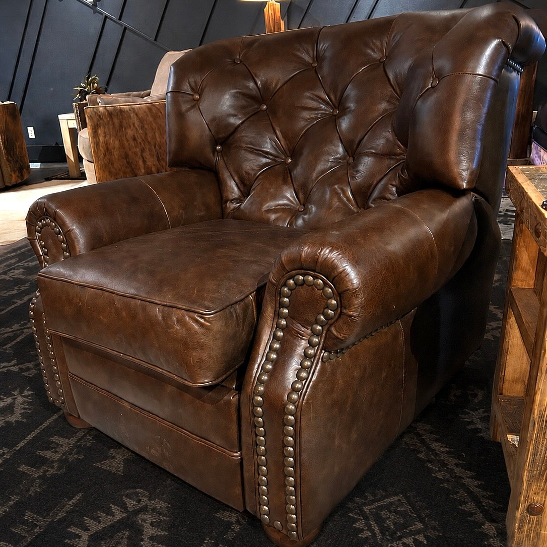 Brown leather recliner chair in a room with wooden furniture and dark walls.