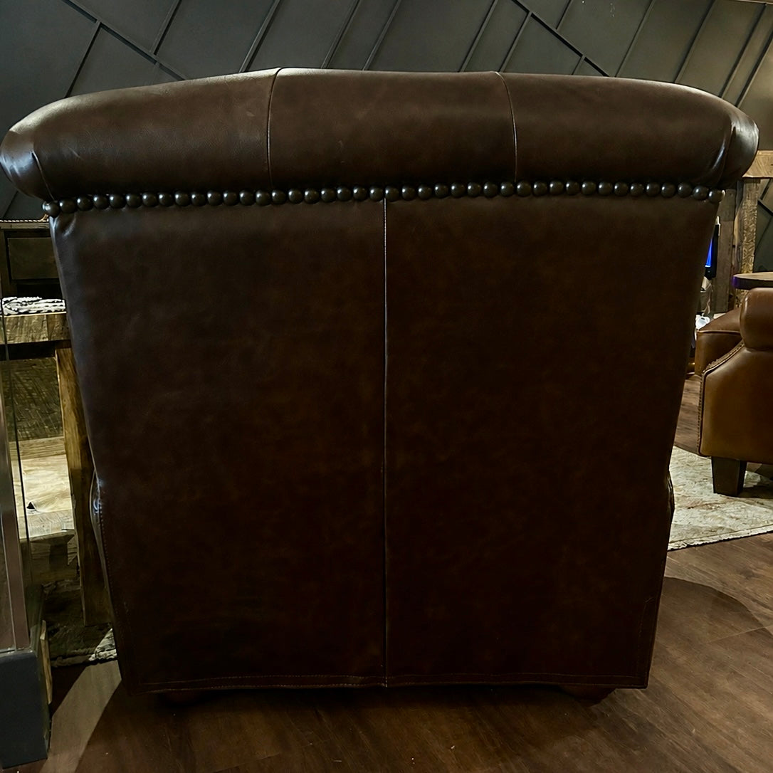 Brown leather armchair in a room with wooden floor and walls.