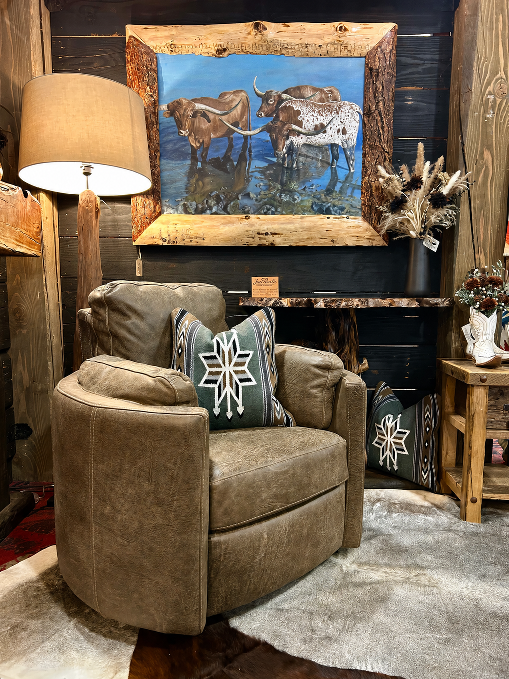 Grey armchair with decorative pillows in a rustic room setting with artwork and decor.