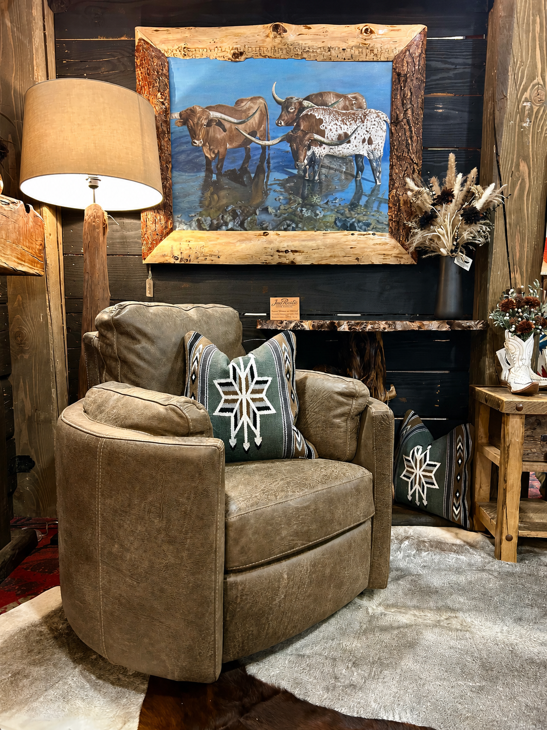 Grey armchair with decorative pillows in a rustic room setting with artwork and decor.