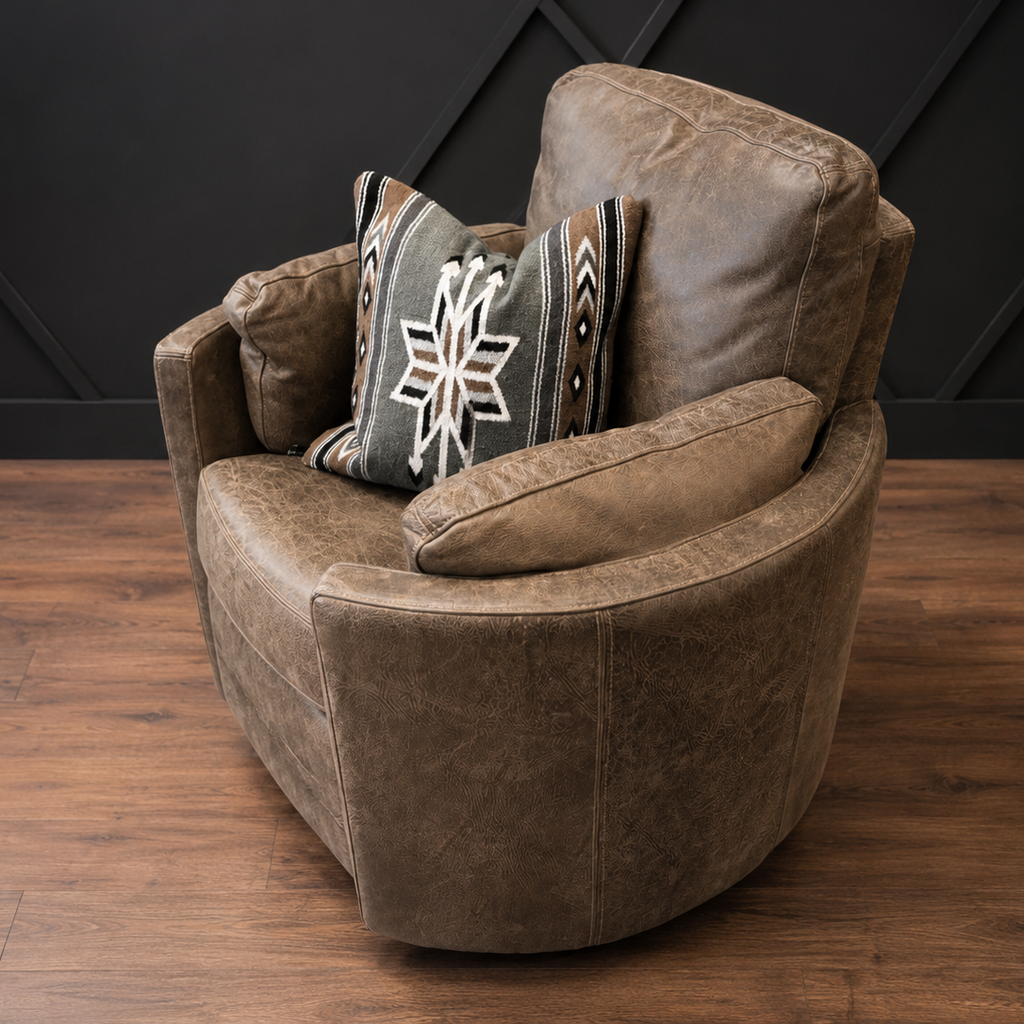 Gray armchair with patterned cushions on a wooden floor against a black paneled wall.