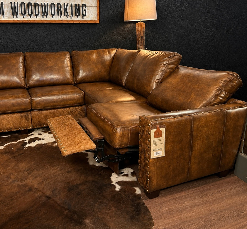 Brown leather sectional sofa in a room with a cowhide rug and lamp.