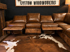 Brown leather sectional sofa in a room with a cowhide rug and 'Custom Woodworking' sign.