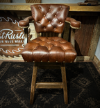 Brown leather barstool with button tufting and cowboy tooled leather.