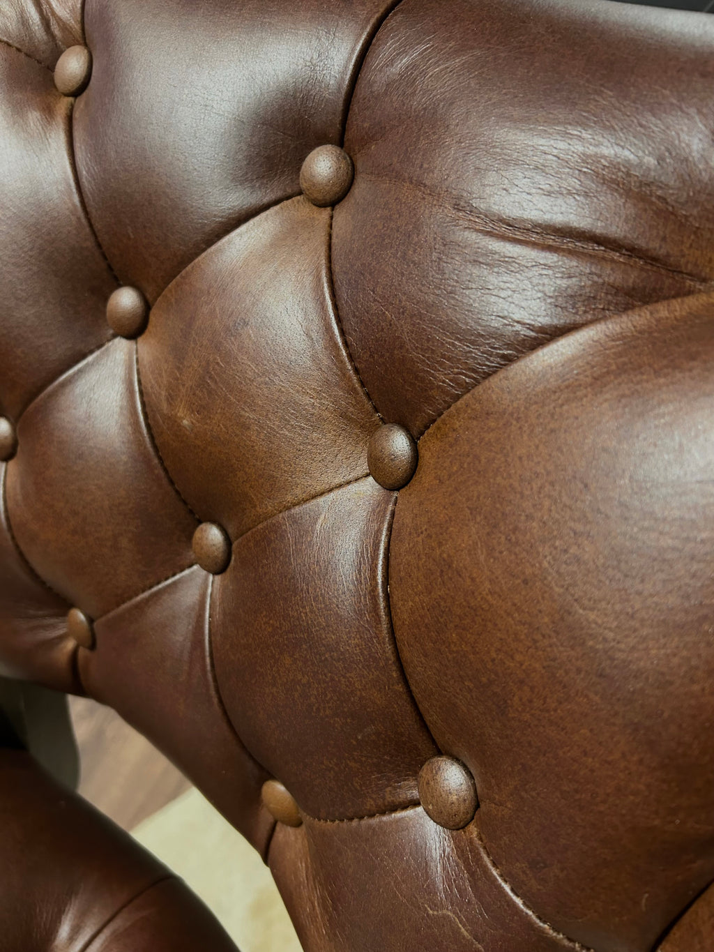 Brown leather barstool with button tufting and cowboy tooled leather.