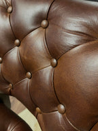 Brown leather barstool with button tufting and cowboy tooled leather.