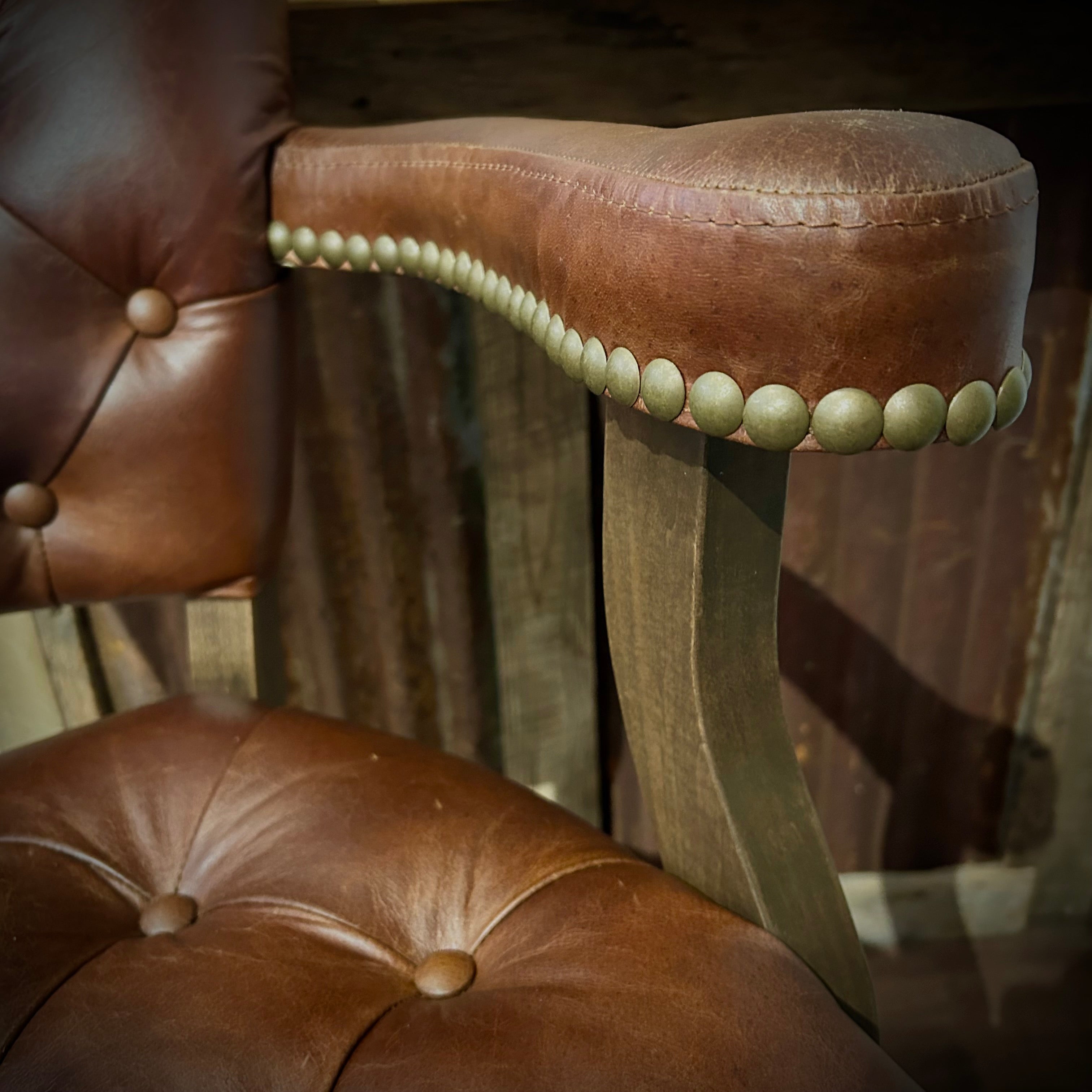Brown leather barstool with button tufting and cowboy tooled leather.
