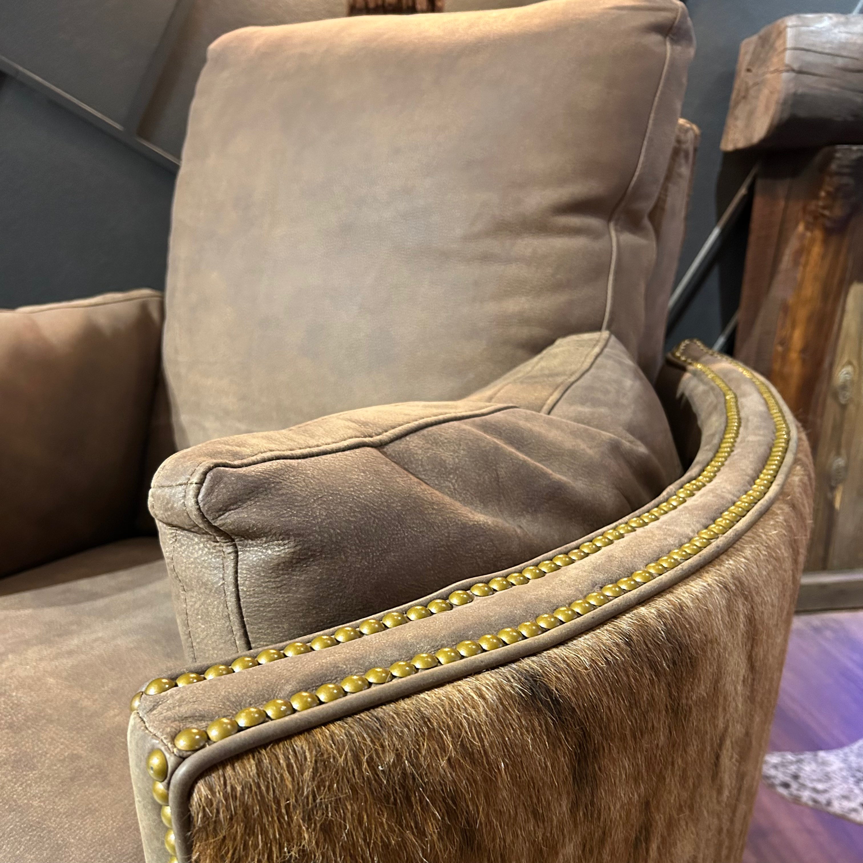 Brown leather recliner with cowhide arms and back.