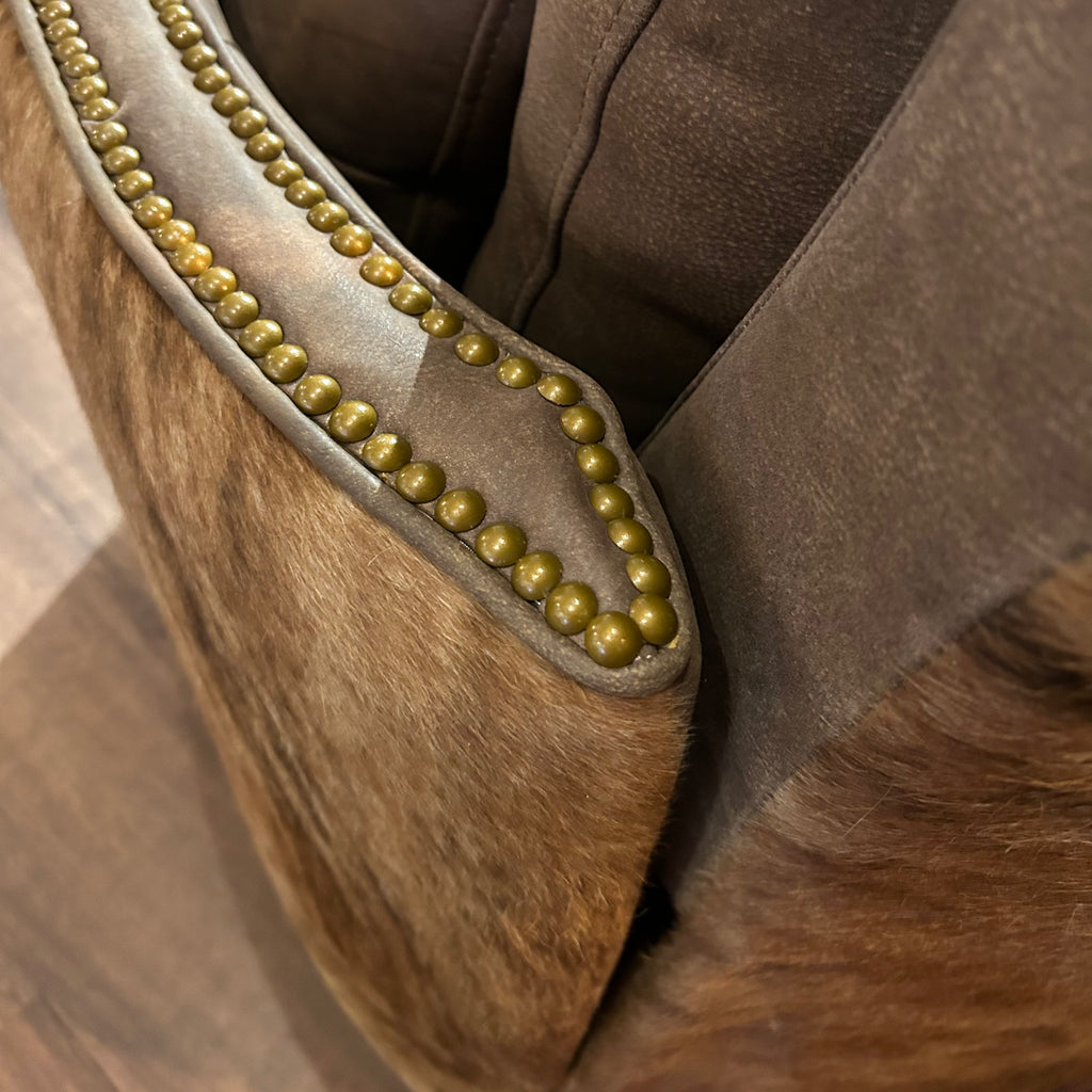 Brown leather recliner with brass neailheads and cowhide arms and back.