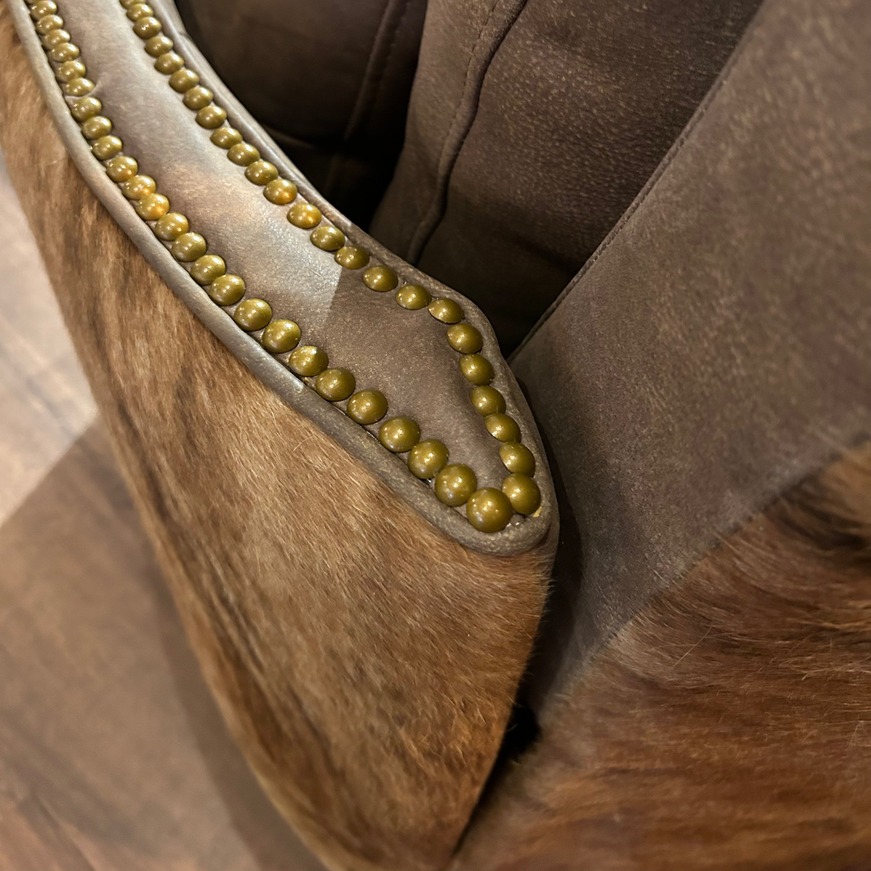 Brown leather recliner with brass neailheads and cowhide arms and back.