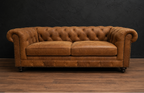 Brown leather sofa against a dark wall on a wooden floor