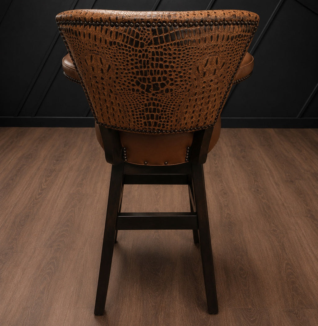 Brown leather barstool with embossed crocodile accents against a black paneled wall.