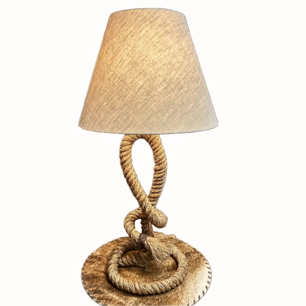 Natural rope table lamp with looped stem, knotted detailing, and neutral cotton shade against a white background.