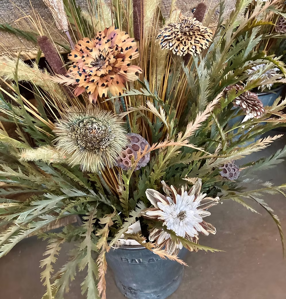 Detail of five oversized feather flowers and textured greenery in the Bucket Wowie arrangement