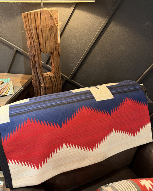 Navy, red, and cream Western geometric blanket draped over a leather sofa